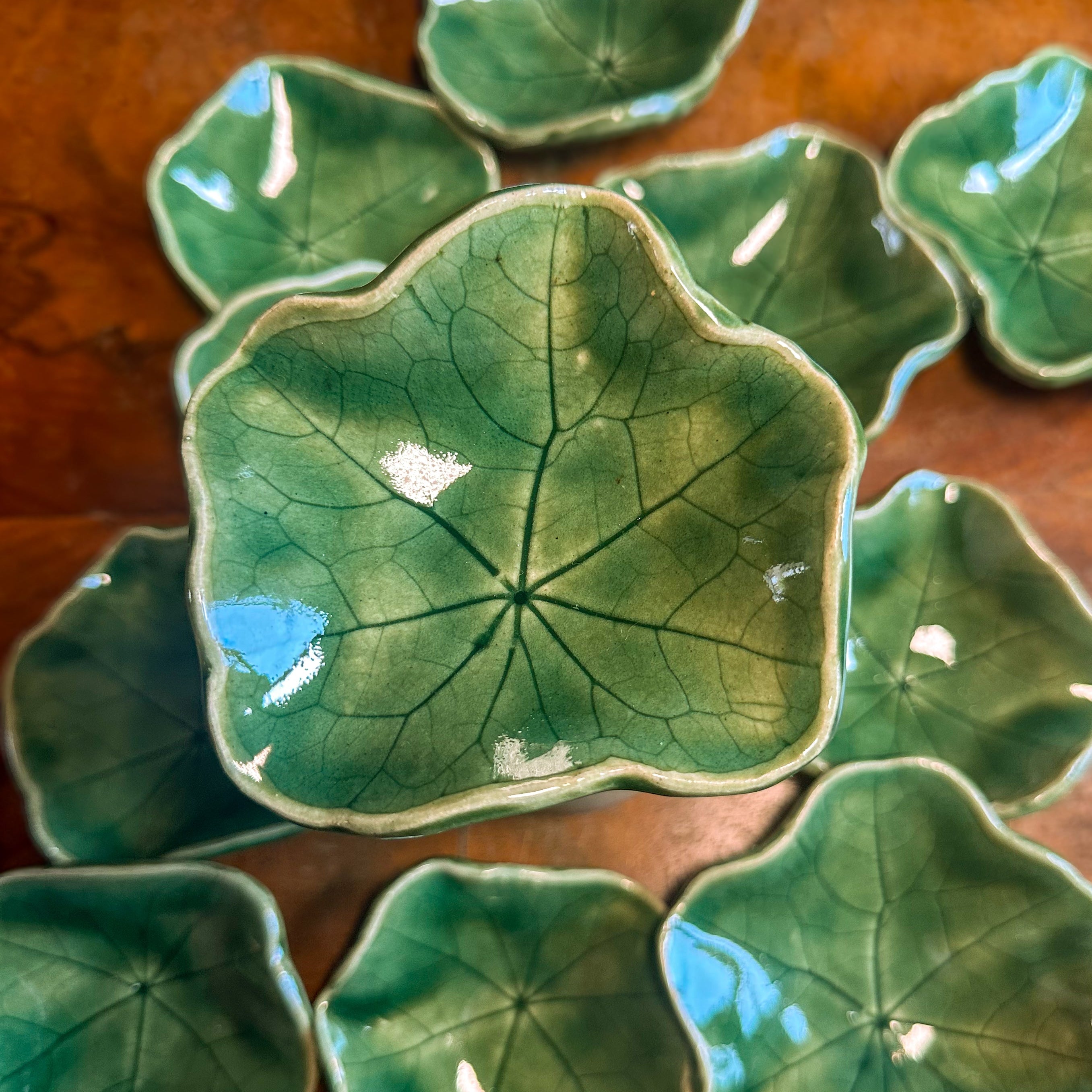 Set of green ceramic leaf-shaped dishes on a wooden surface