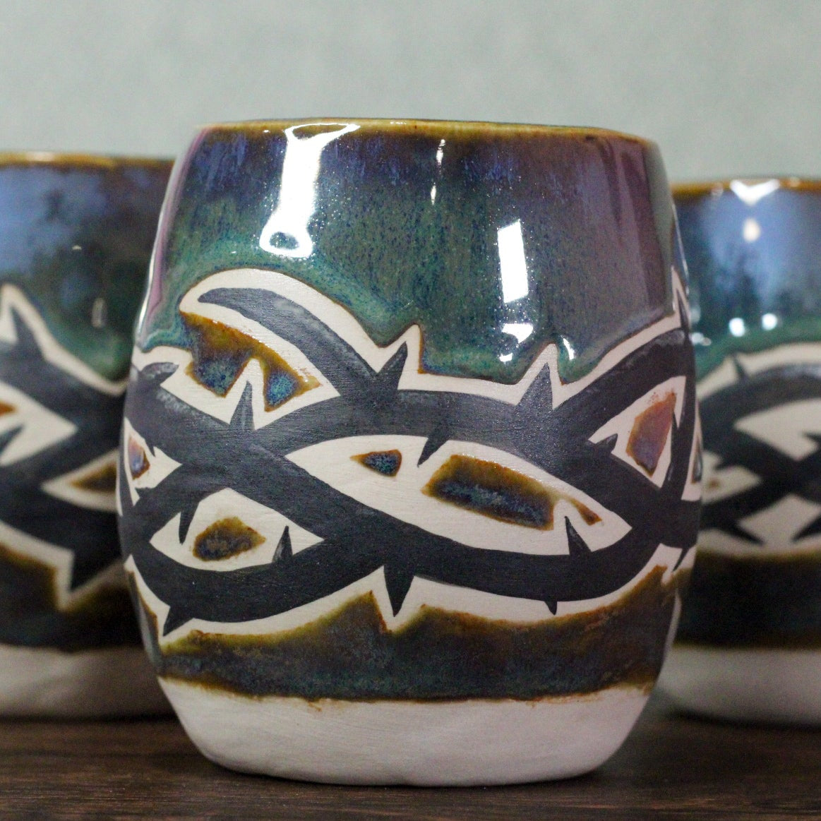 Three ceramic cups, with a black thorny band round the middle.